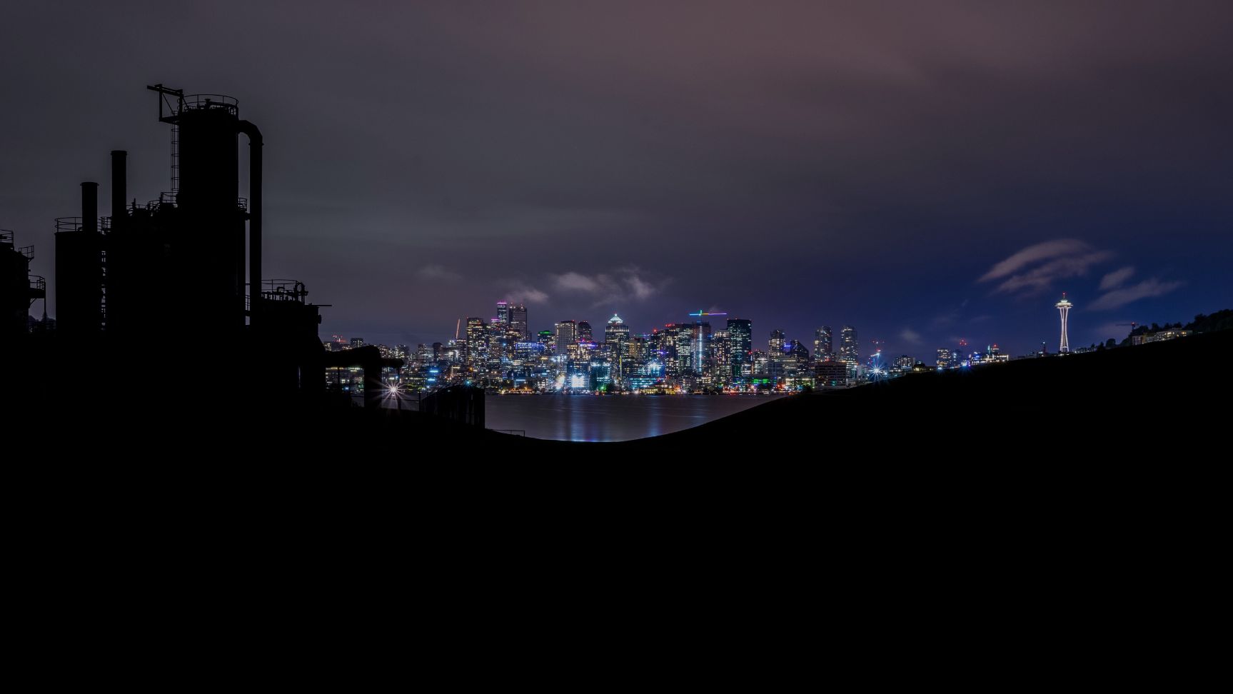 Image shows Seattle skyline at night with silhouette of Gas Works Park. Photo taken by Chad Peltola. Source https://unsplash.com/photos/FLppEGjsVaM